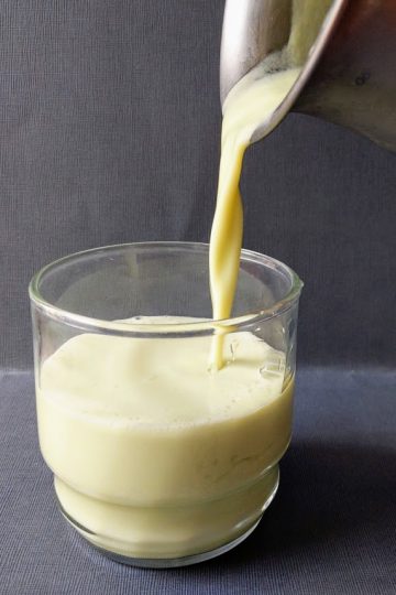 avocado smoothie is poured from a pitcher into a glass