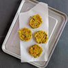 Four zucchini patties in a tray with parchment paper