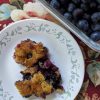 Cobbler served on a plate with blueberries on the side