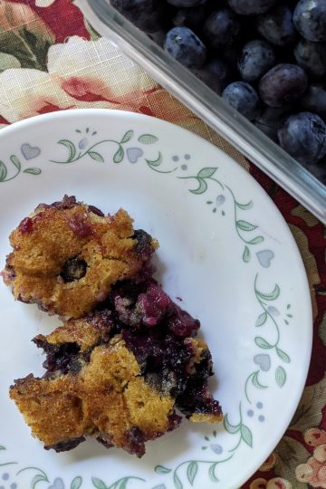 Cobbler served on a plate with blueberries on the side