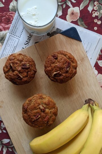 Banana Nut Muffins on cutting board with bananas and milk, bird’s eye view