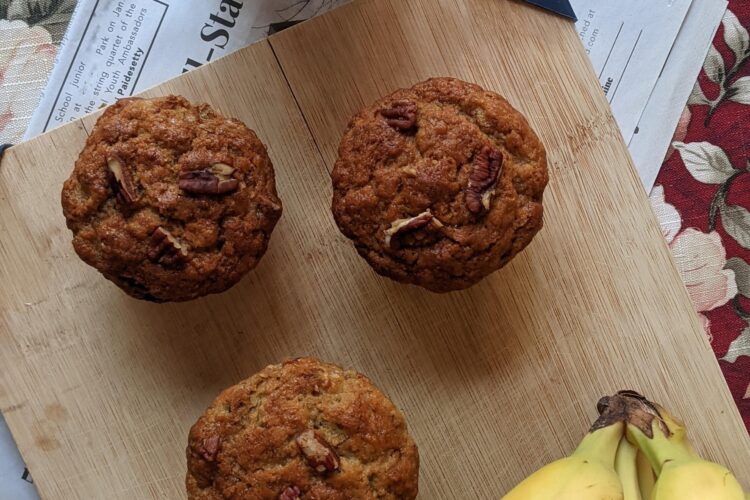 Banana Nut Muffins on cutting board with bananas and milk, bird’s eye view