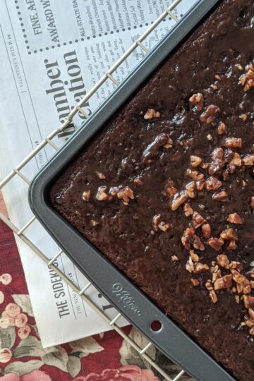 Small Batch Texas Sheet Cake in tray on cooling rack, newspaper in background