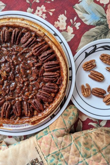 Pecan Pie in tin with plate of pecans, top view