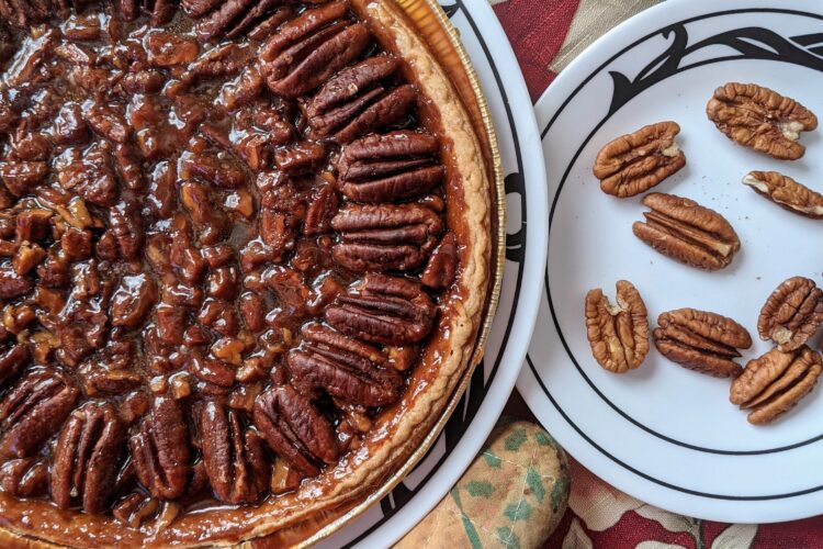 Pecan Pie in tin with plate of pecans, top view