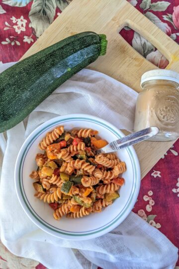 Roasted vegetable rotini from above, on cutting board with zucchini and black pepper