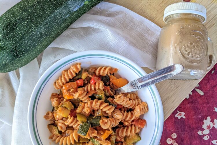 Roasted vegetable rotini from above, on cutting board with zucchini and black pepper