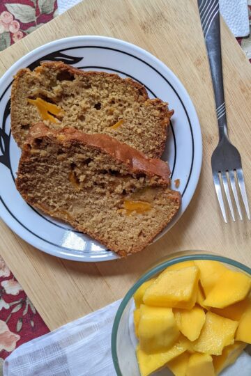 Vegan Mango Bread slices top view with mango bowl on cutting board