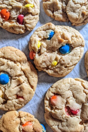 Eggless M&M Cookies spread out on parchment paper top view
