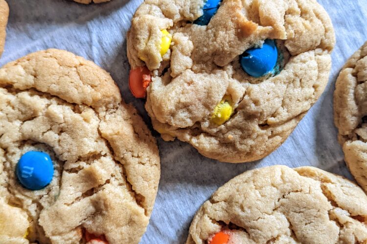 Eggless M&M Cookies spread out on parchment paper top view