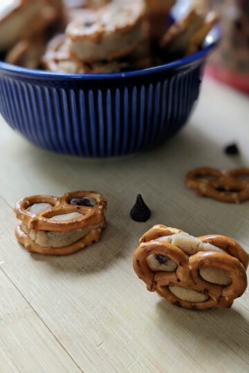 Cookie Dough Pretzel Bites on cutting board with blue bowl in distance