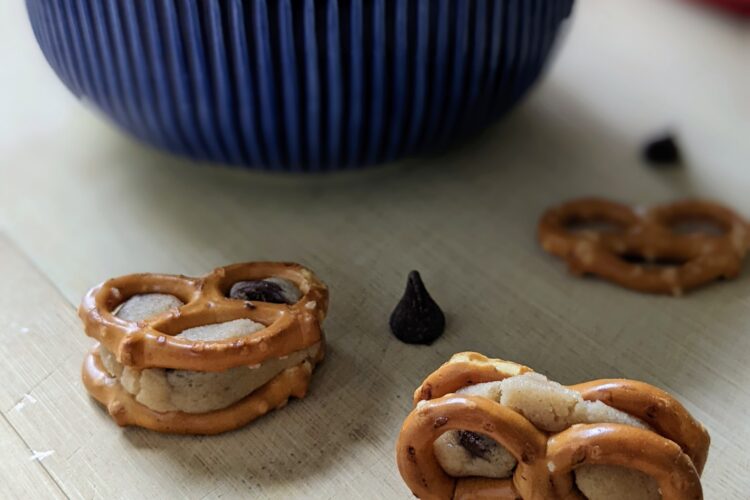 Cookie Dough Pretzel Bites on cutting board with blue bowl in distance